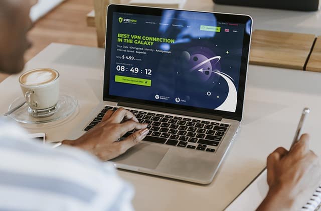 Someone sitting at a desk with a close up of the laptop. The page has a title 