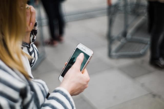 Girl holding a smart phone on the street