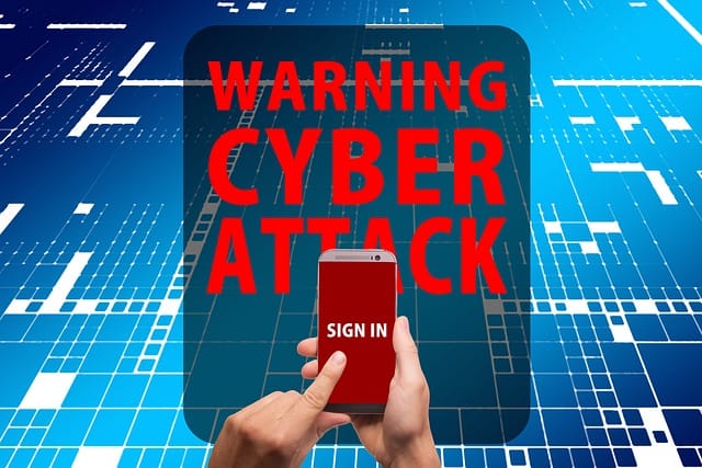 Warning of Cyber Attack, with a phone in a mans hands, he's pointing to the screen which says 