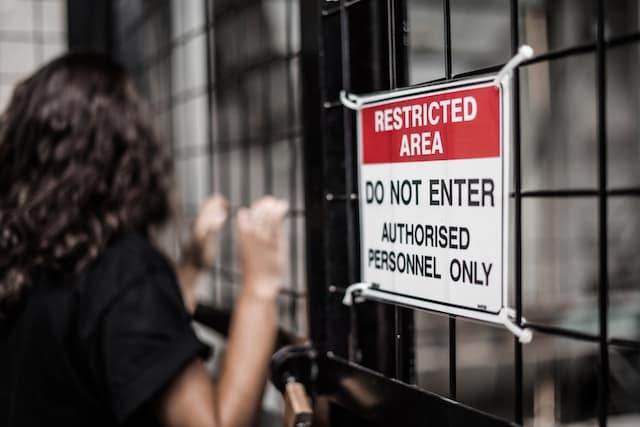 Woman at a fence that also has a sign that reads 