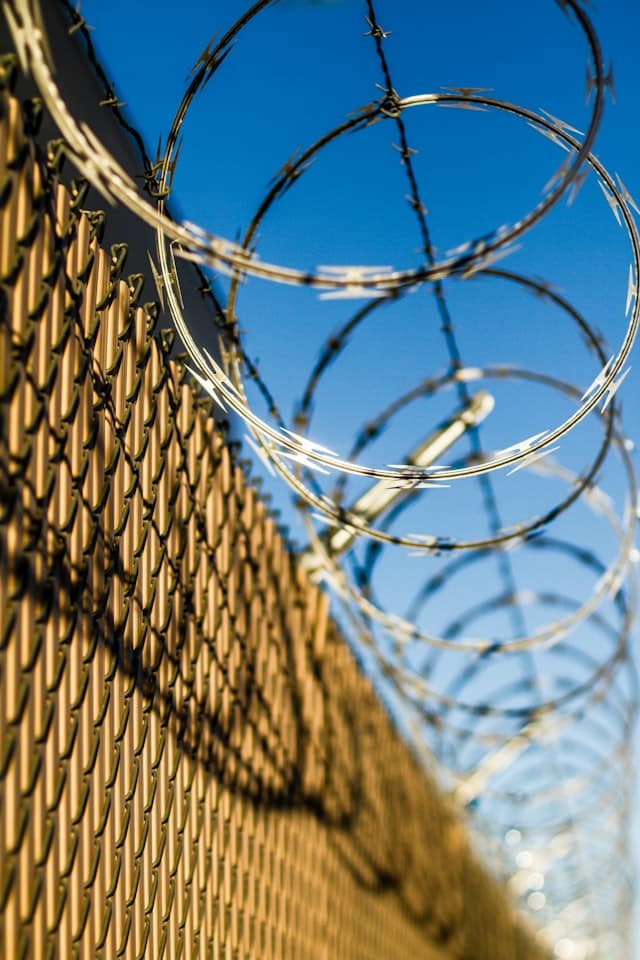 Close up of a fence with barbed-razor wire at the top.