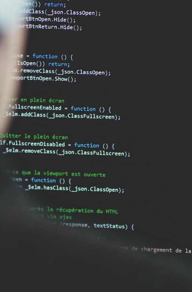 Blurred out person barely visible to the left of the image, the focus is on a screen of code.