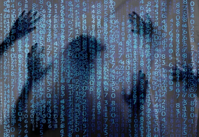 Blue Matrix-like text on the screen, but there's shadows of humans behind it, like a see-through screen.