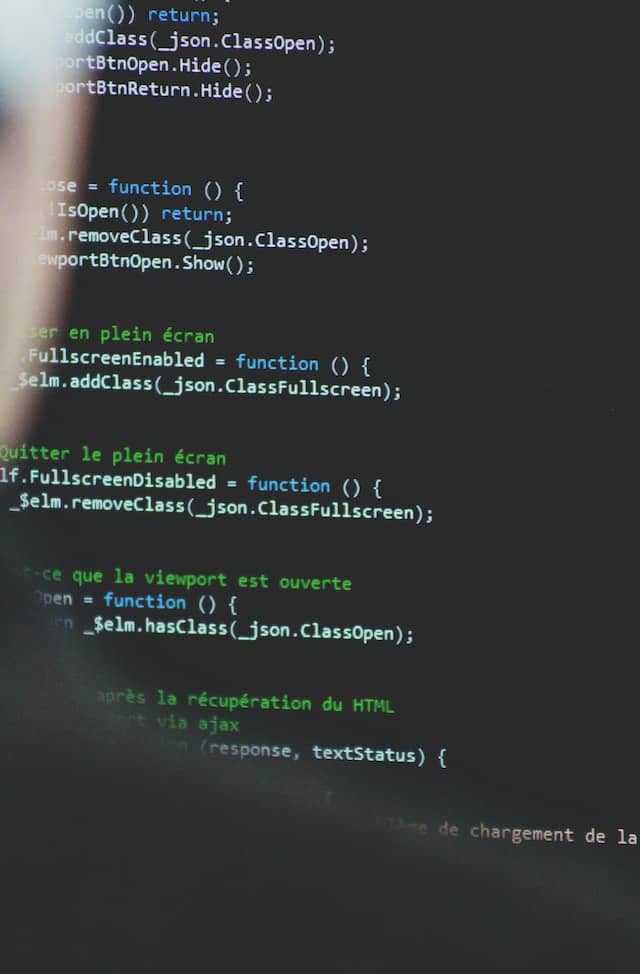 Blurred out person barely visible to the left of the image, the focus is on a screen of code.